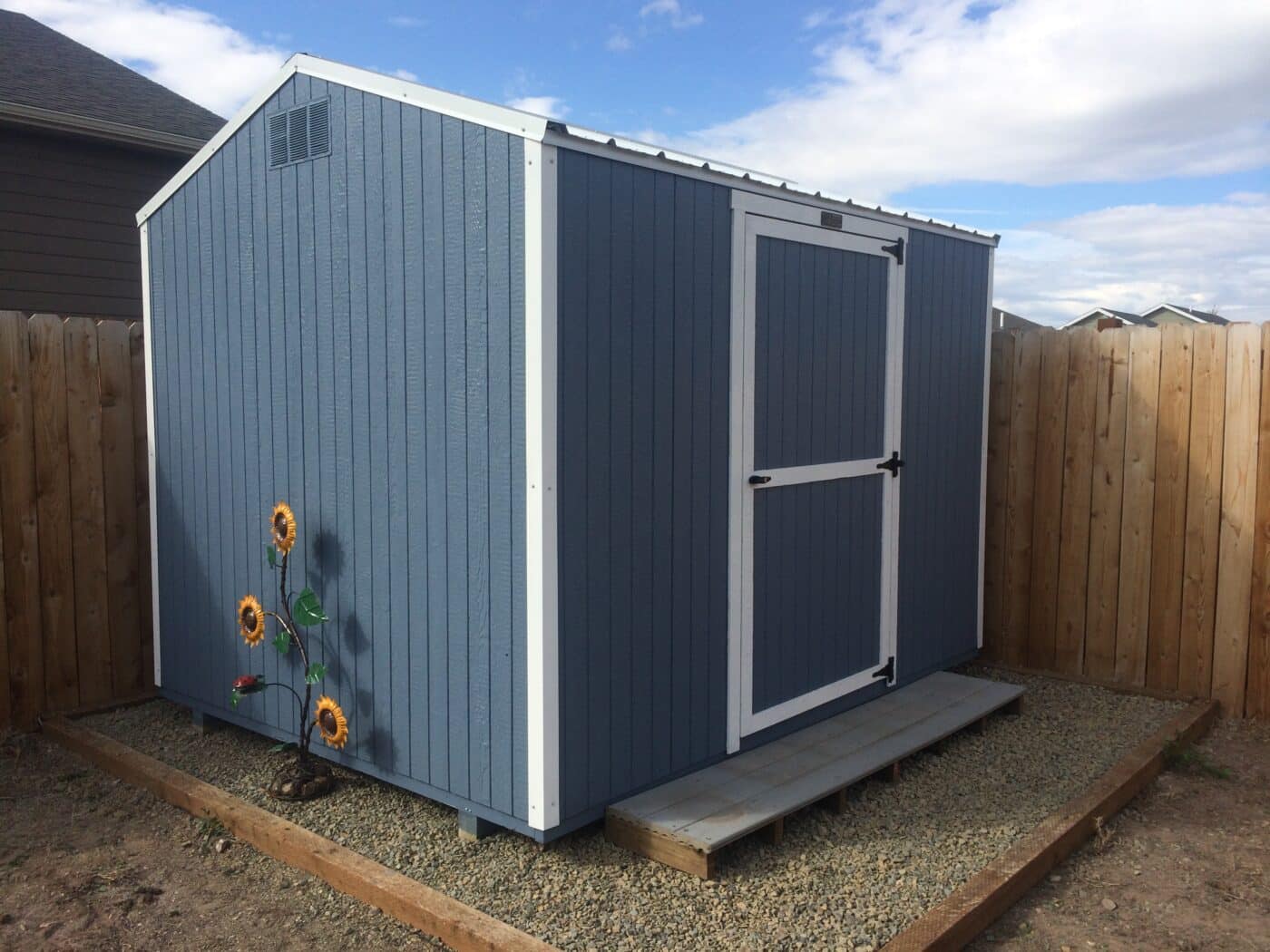 blue economy shed with white trim on gravel pa foundation