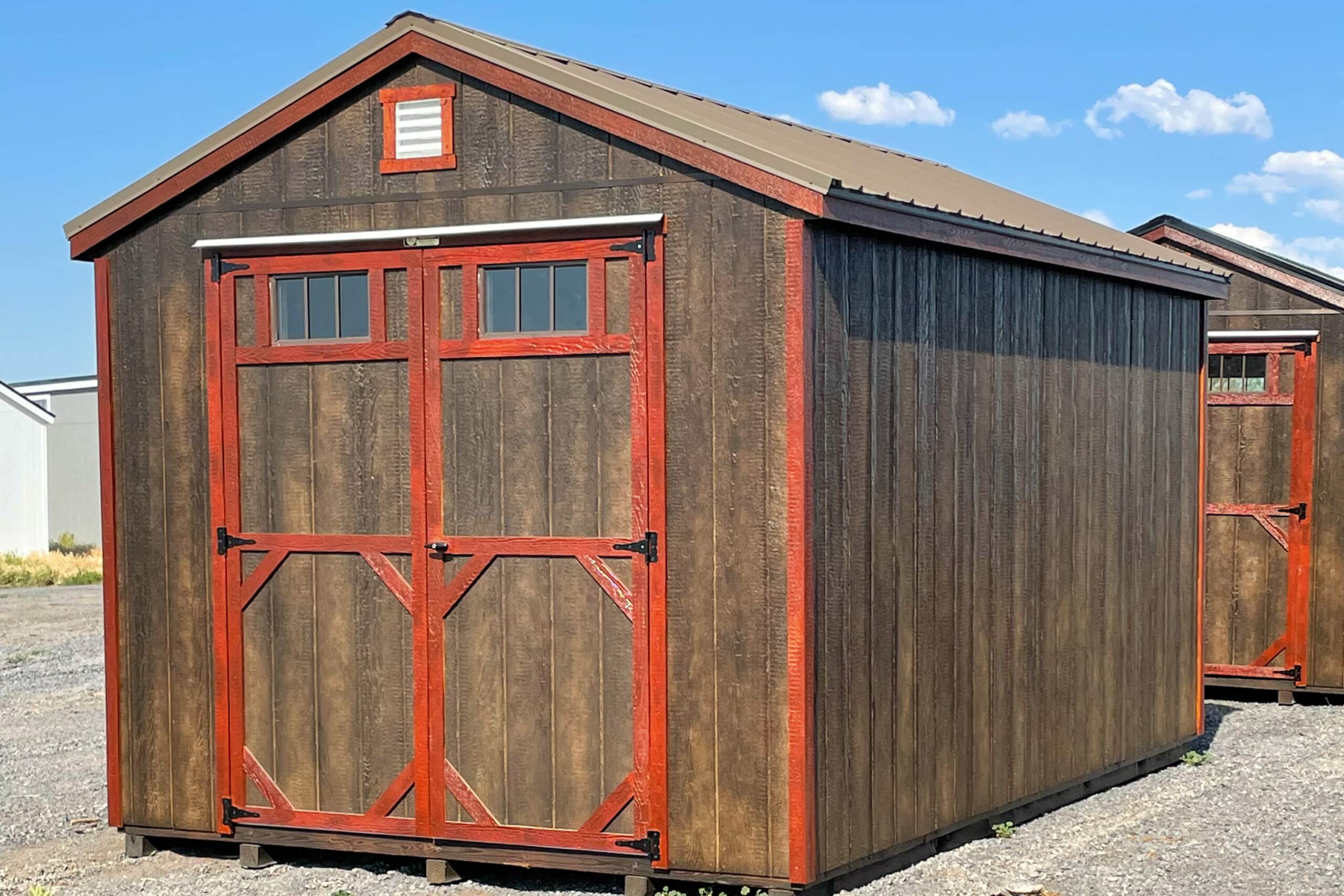 brown and red trimmed utility sheds in Surrey ND sales lot