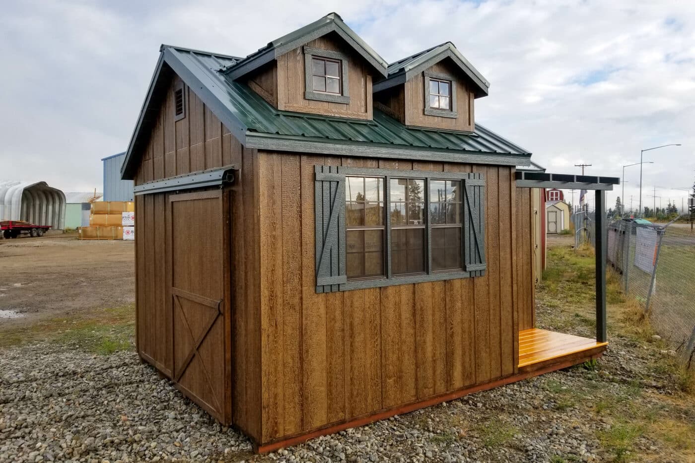 brown bear paw shed with porch three windows and green metal roof