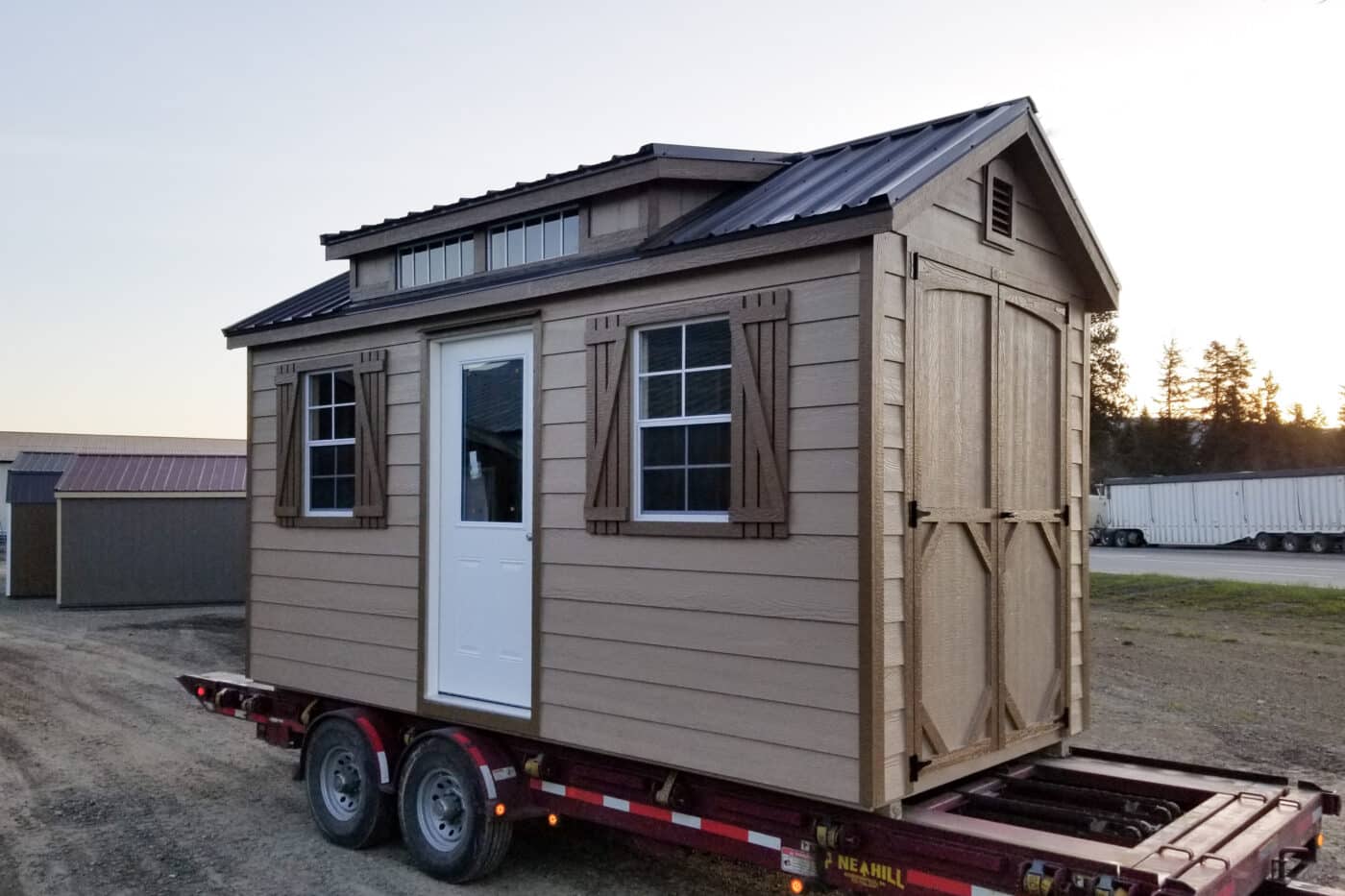 light brown shed with darker brown trim and dark brown metal roofing with dormer