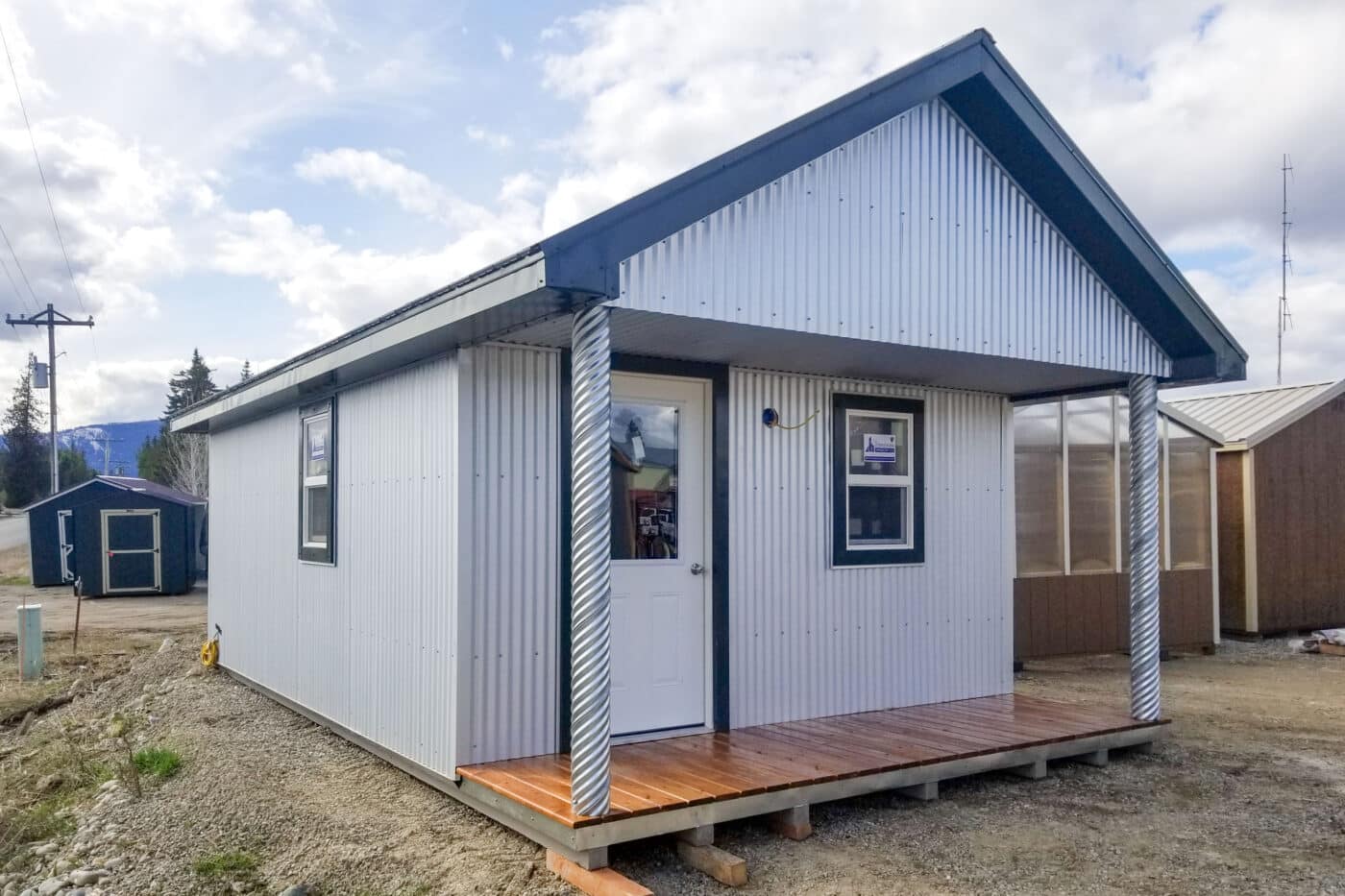 metal sheds with black roof and small front porch with wooden flooring