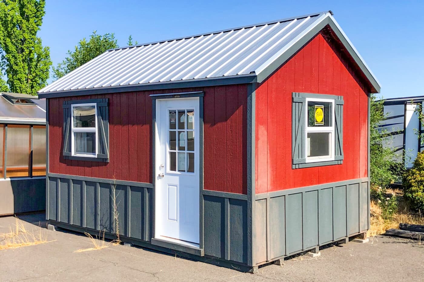 red mountain shed with blue gray strip on bottom trim and metal roof with two windows