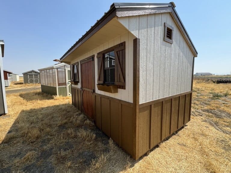 tan and chestnut brown sided 8x14 quaker garden shed in Klamath Falls OR with chestnut brown trim and a red mahogany door with two windows with chestnut brown shutters and a metal burnished slate roof