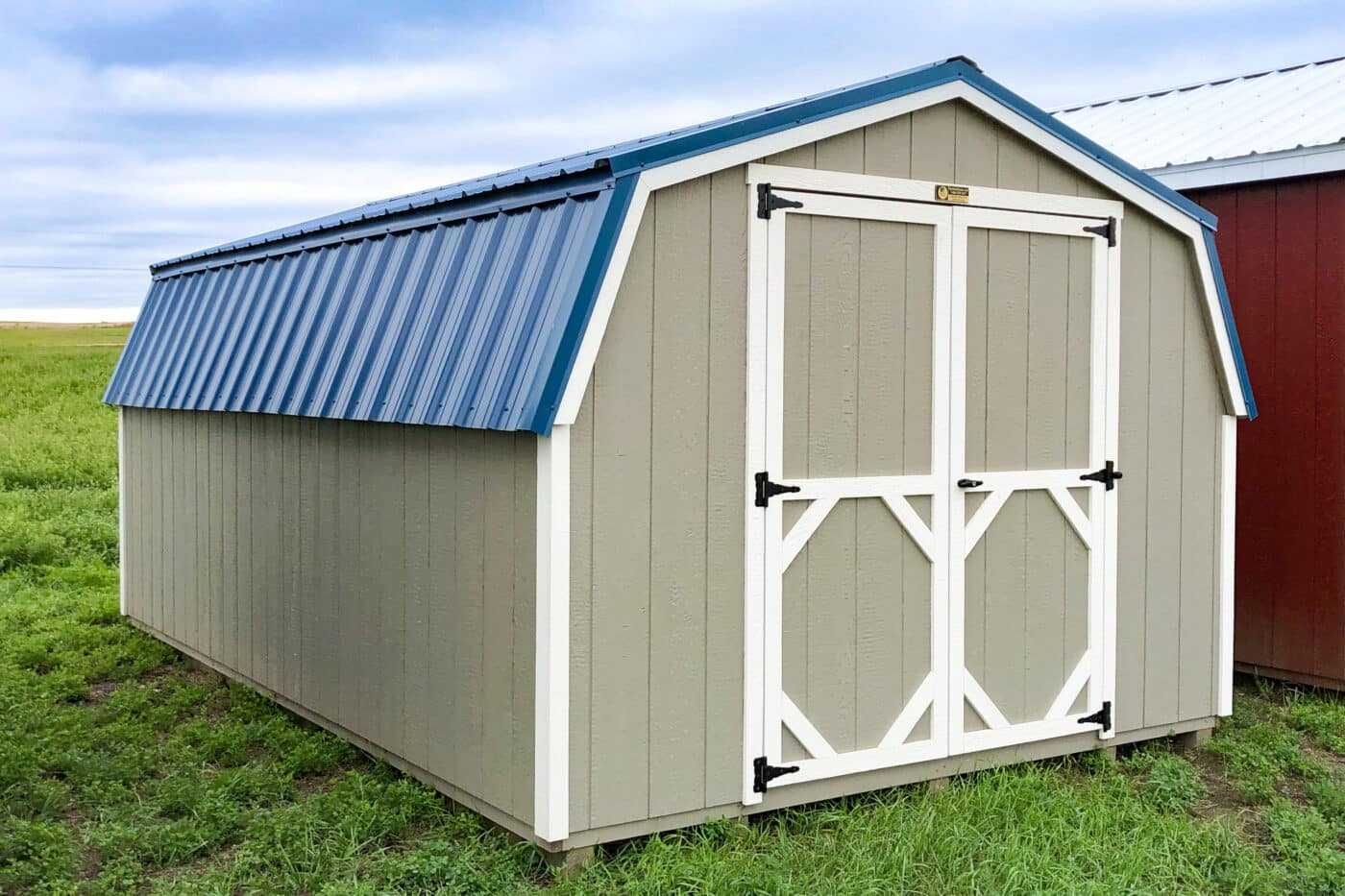 tan barn style shed with blue metal roof and white trim built after acquiring shed permits in Oregon