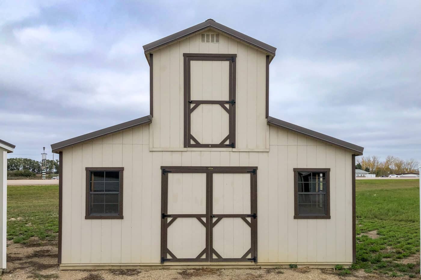 tan monitor barn shed with brown trim two windows and a second story that requires shed permits in Washington